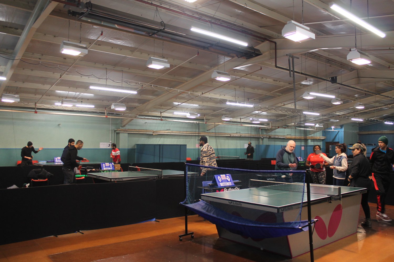 A group of 9 people playing table tennis indoors