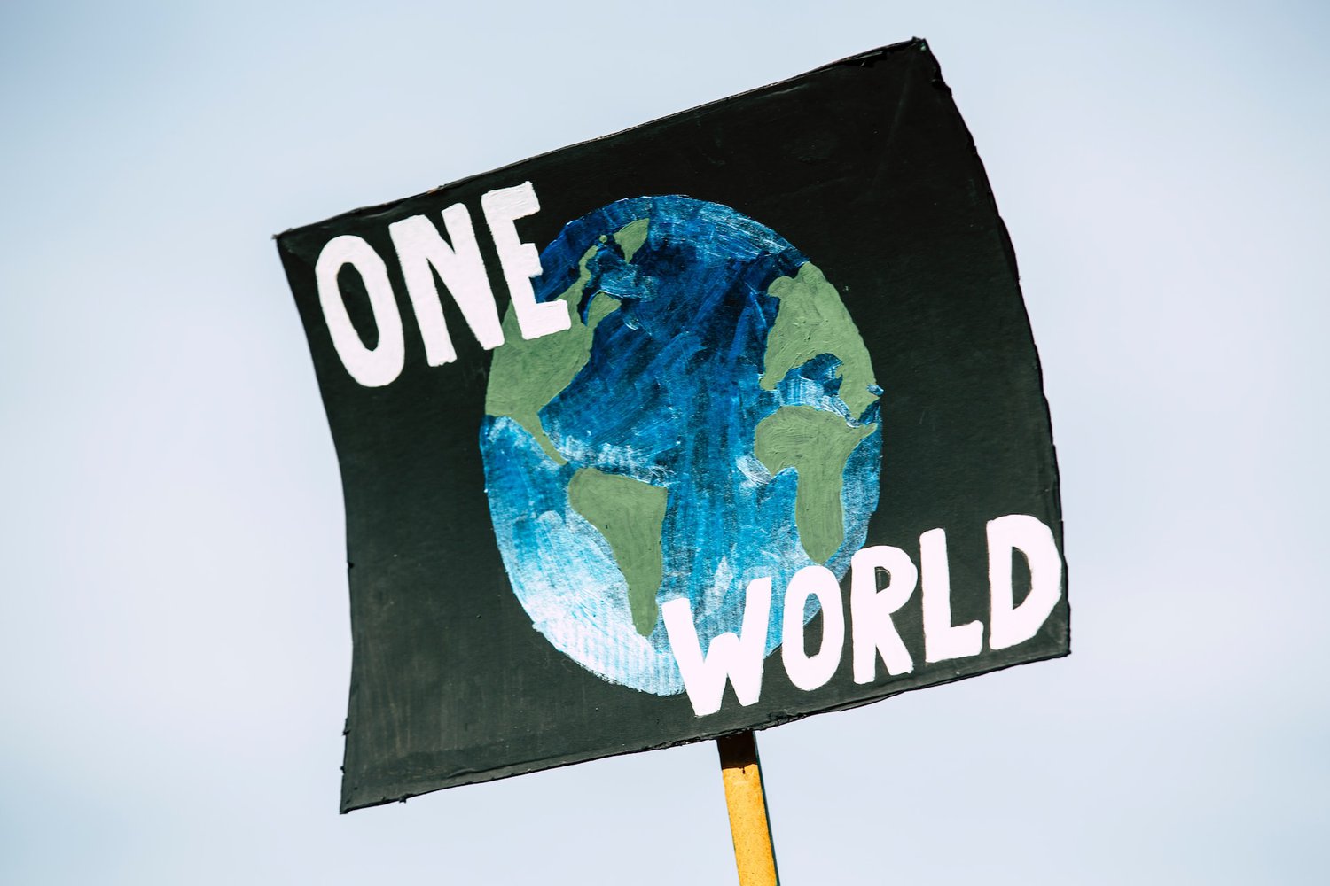 Black banner with a collage of earth and white text reading: One World