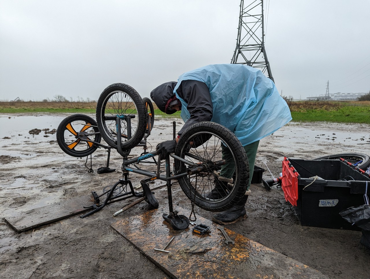 A man in a waterproof covering repurposes a working bike from two broken ones